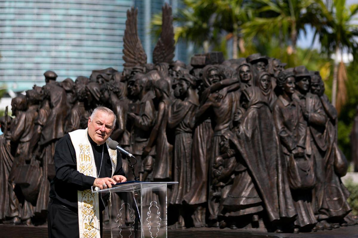 Archbishop Thomas Wenski speaks next to a sculpture titled “Angels Unawares,” at Bayfront Park in downtown Miami on Wednesday, February 10, 2021. The traveling bronze, life-sized sculpture will be open to the public daily for viewing until April 8. The sculpture weighs four tons and is 20-feet long. It features indigenous people, Jews fleeing Nazi Germany, Joseph, Mary, Jesus, and much more.