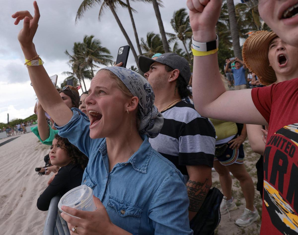 Elana Shalem, 25, left, can not hold her excitement as the crowd react to the aerobics by professional motorcycle riders. On Sunday, May 29, 2022 motorcycle acrobatics met military precision in South Beach Sunday, as an Air Force honor guard performed drills on the sand as professional motorcross drivers jump their bikes 70 feet above in Lummus Park in South Beach.