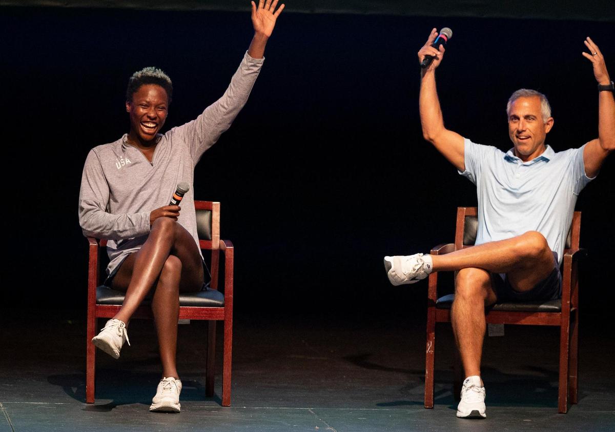 Ashleigh Johnson, Team USA water polo goalkeeper and Ransom alum, left, waves to students with Adam Krikorian, the Team USA women’s water polo coach, during a talk with Ransom Everglades students on Tuesday, Dec. 5, 2023, at the school auditorium in Coconut Grove. Team USA has been training at Ransom in preparation for their upcoming matches that week against Spain.
