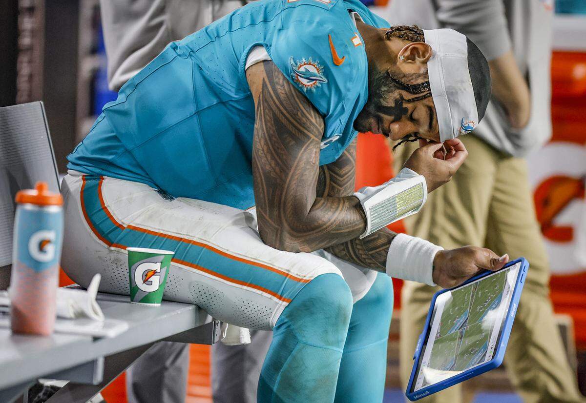 Miami Dolphins quarterback Tua Tagovailoa (1) on the bench during the final minutes of the fourth quarter of an NFL football game against the Baltimore Ravens at Hard Rock Stadium on Thursday, October 30, 2025, in Miami Gardens, Florida.