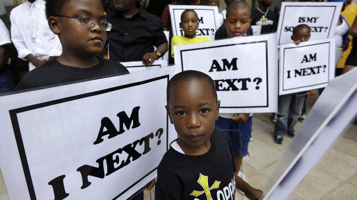 Alvin Duplessis, 10, left, and Thomas McGriff, 5, hold signs during a New Orleans rally held after George Zimmerman’s acquittal in this 2013 file photo.