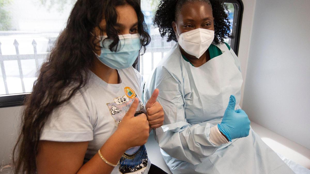 Jenna Ramkhelawan, de 12 años, a la izquierda, muestra el pulgar hacia arriba, junto con Delores Fye, LPN de UM Health, después de recibir su primera dosis de la vacuna de Pfizer el martes 18 de mayo de 2021. 