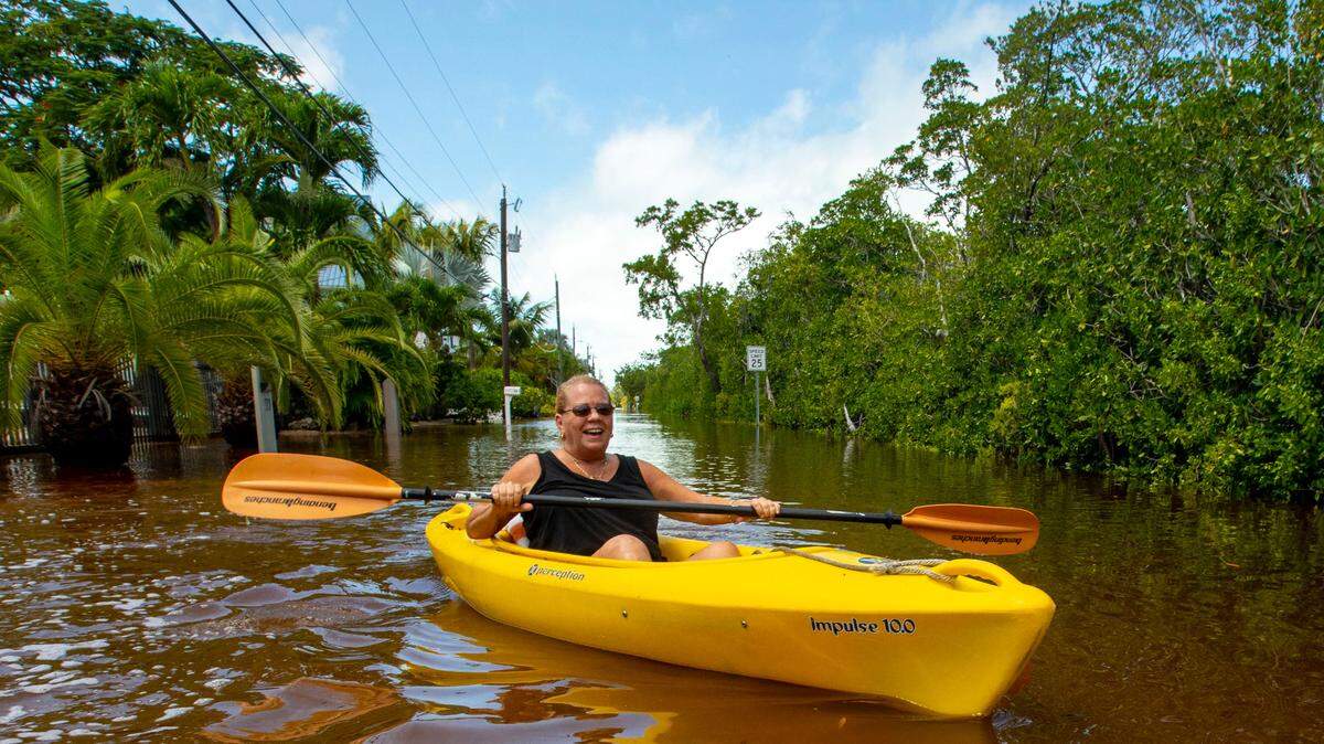 Kimberly Glenn, 57, kayaks up North Blackwater Lane on a trip to the store for a pack of cigarettes while the street was flooded due to the effects of Hurricane Ian at Stillwright Point in Key Largo in 2022. Monroe County has seven ongoing project to raise roads to reduce such impacts.