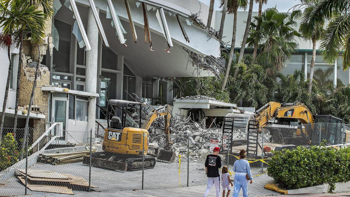 Peatones caminan junto al histórico Deauville Beach Resort en Miami Beach el 13 de marzo de 2022, un día después que los trabajadores comenzaran a derribar el frente del hotel y el letrero rojo metálico.