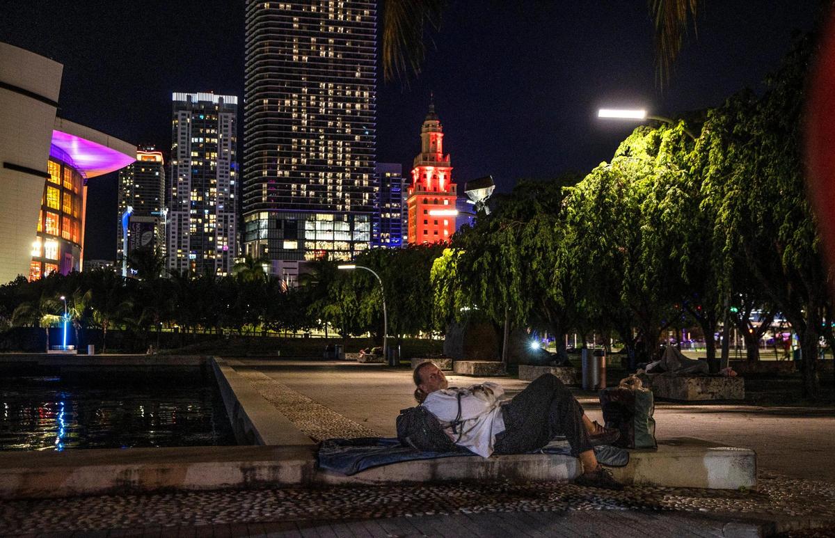 A homeless man lays down on the sidewalk at the Museum Park in downtown Miami, during the Miami-Dade County’s annual Point-in-Time (PIT) Homeless summer census, where different teams conducted the annual summer count of those experiencing homelessness from Homestead to Miami Beach to North Miami, on Thursday August 18, 2022.