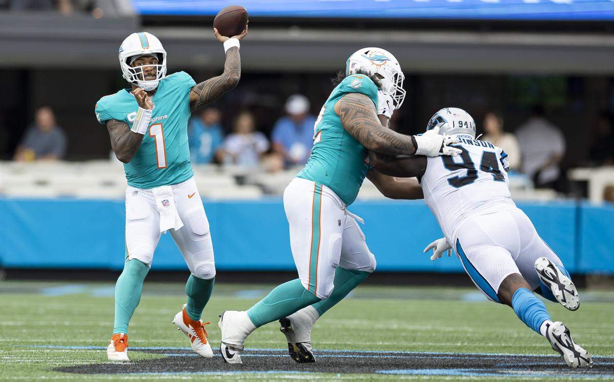 Miami Dolphins quarterback Tua Tagovailoa (1) looks to pass the ball as offensive tackle Jonah Savaiinaea (72) defends against Carolina Panthers defensive end A'Shawn Robinson (94) in the first half of their NFL game at the Bank of America Stadium on Sunday, Oct. 5, 2025, in Charlotte, N.C.
