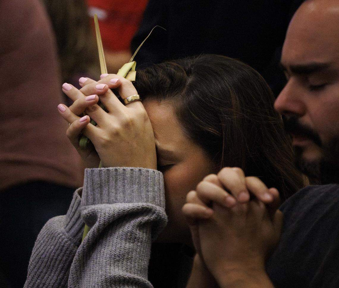A woman prays with palms in her hands after receiving communion during Palm Sunday mass on Sunday, March 29, 2026, at the Cathedral of St. Mary in Miami, Fla. The service began with the traditional blessing of the palms outside the cathedral followed by Mass.