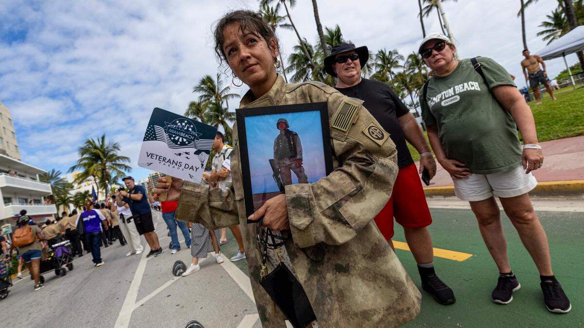 Mio watches the parade as she holds a photo of her late boyfriend, Gerald, who served in the US Military during the 16th Annual Veterans Day Parade off Ocean Drive on Monday, Nov. 11, 2024, in Miami Beach, Fla.