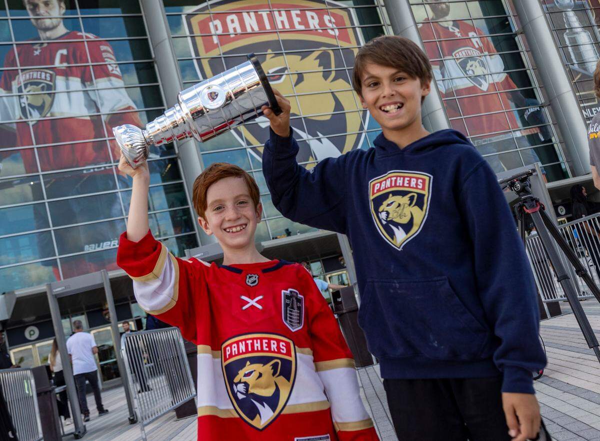 Brothers Ben Lagunov, right, and Jensen Lagunov hoist their own Stanley Cup in front of Amerant Bank Arena.