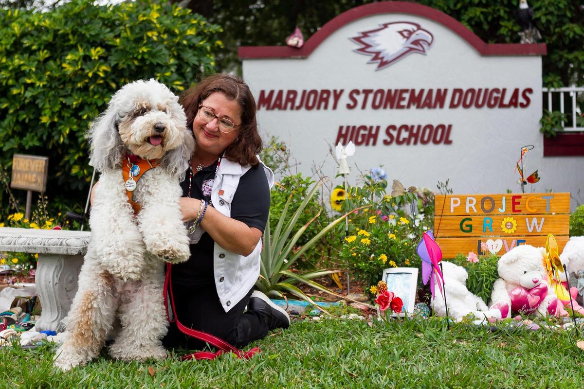 Librarian Diana Haneski, holds River, the Marjory Stoneman Douglas High School therapy dog, near the school’s Grow Love garden in Parkland on Wednesday, April 21, 2021.