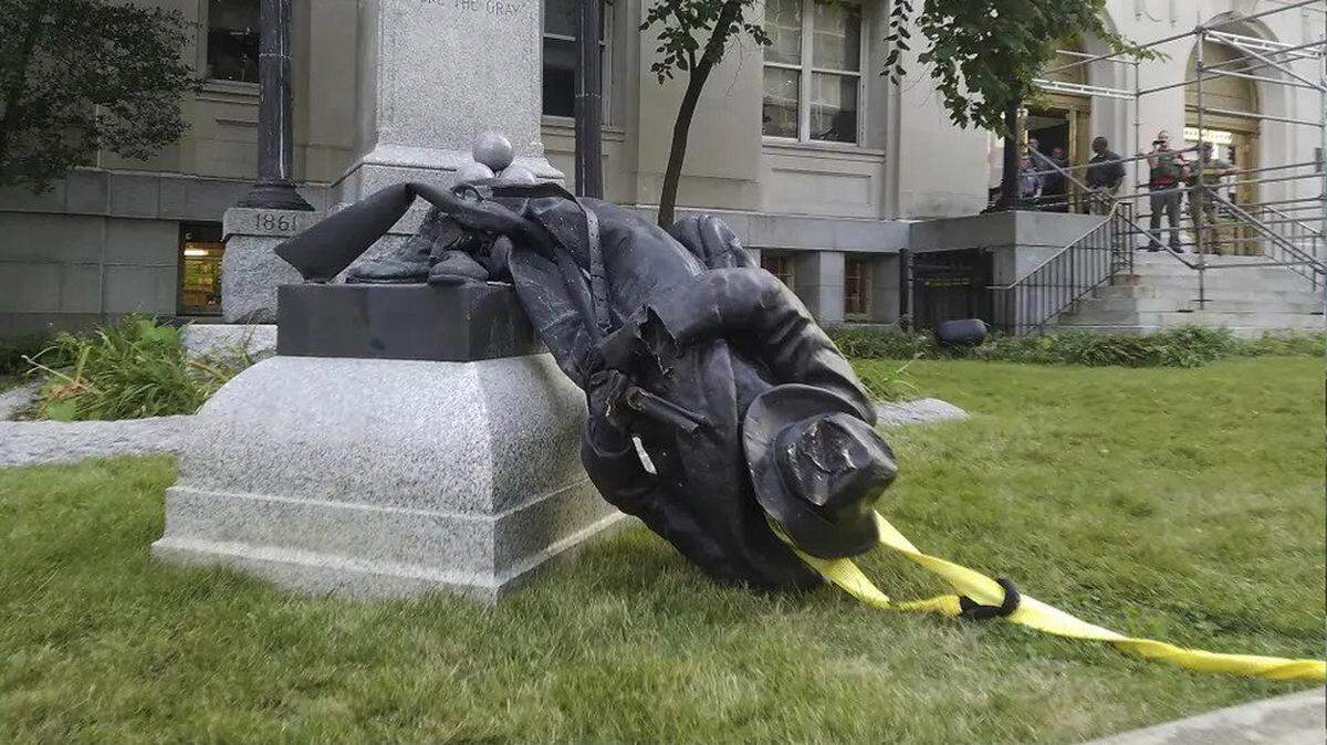 A Confederate statue lies crumpled on the ground in Durham, North Carolina where activists pulled it down after violence in Charlottesville, Virginia. Others have been toppled in a new round of protests after George Floyd’s death.