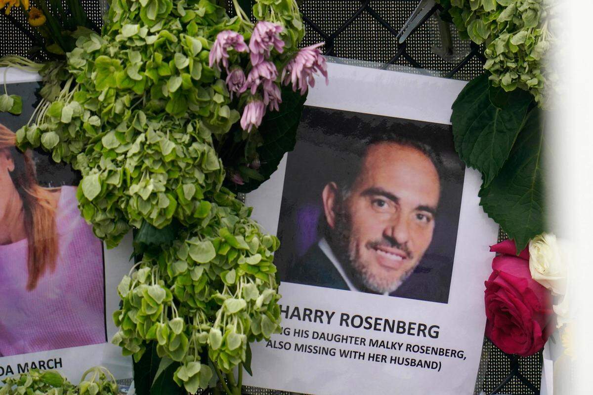 An image of Harry Rosenberg, who died in the oceanfront condo building collapse in Surfside, hangs on a fence as part of a makeshift memorial.