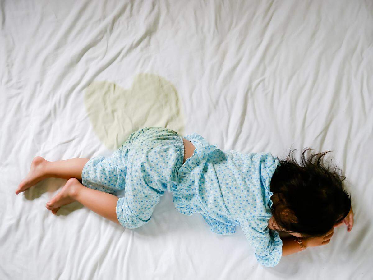 young child wets bed on mattress
