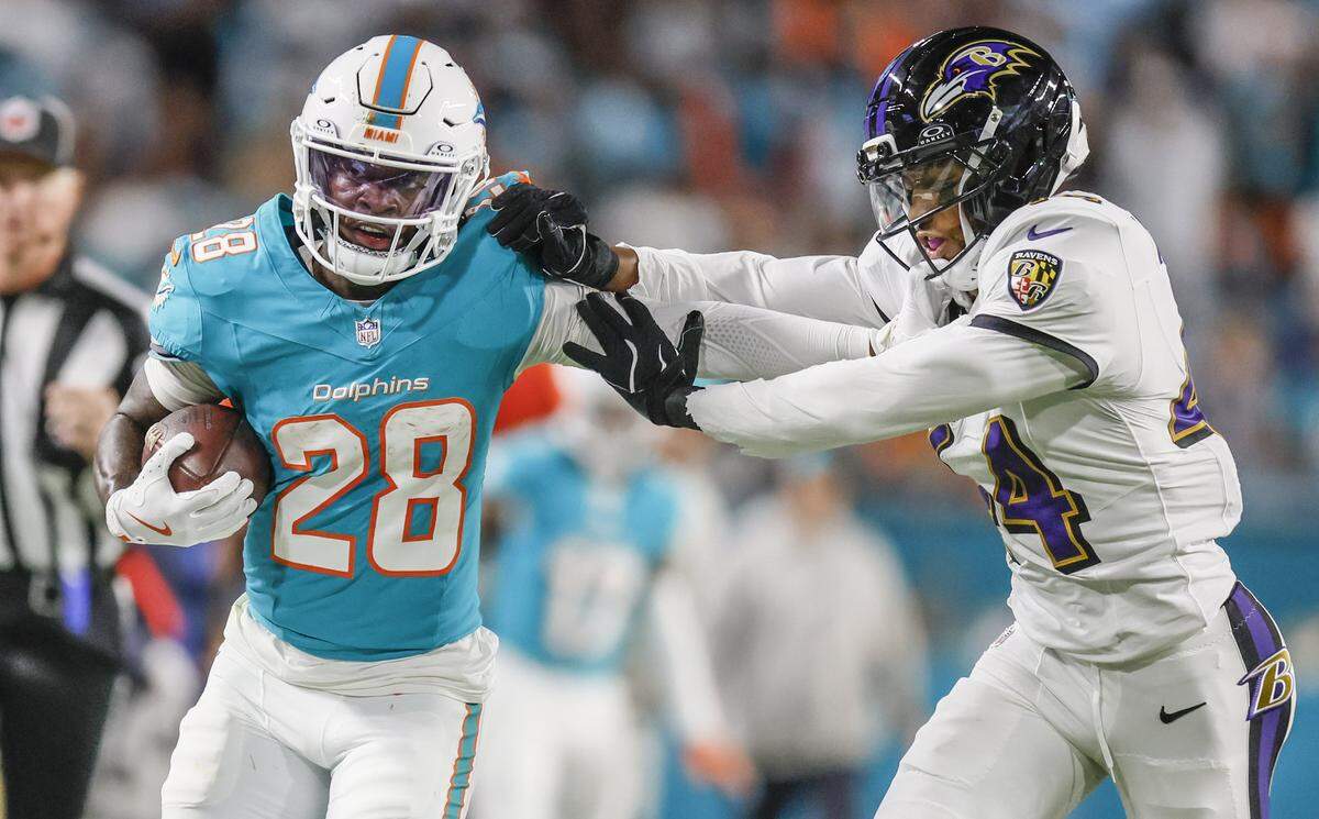 Miami Dolphins running back De'Von Achane (28) battles for yardage on a pass reception against Baltimore Ravens cornerback Marlon Humphrey (44) during the first half of an NFL football game at Hard Rock Stadium on Thursday, October 30, 2025, in Miami Gardens, Florida.