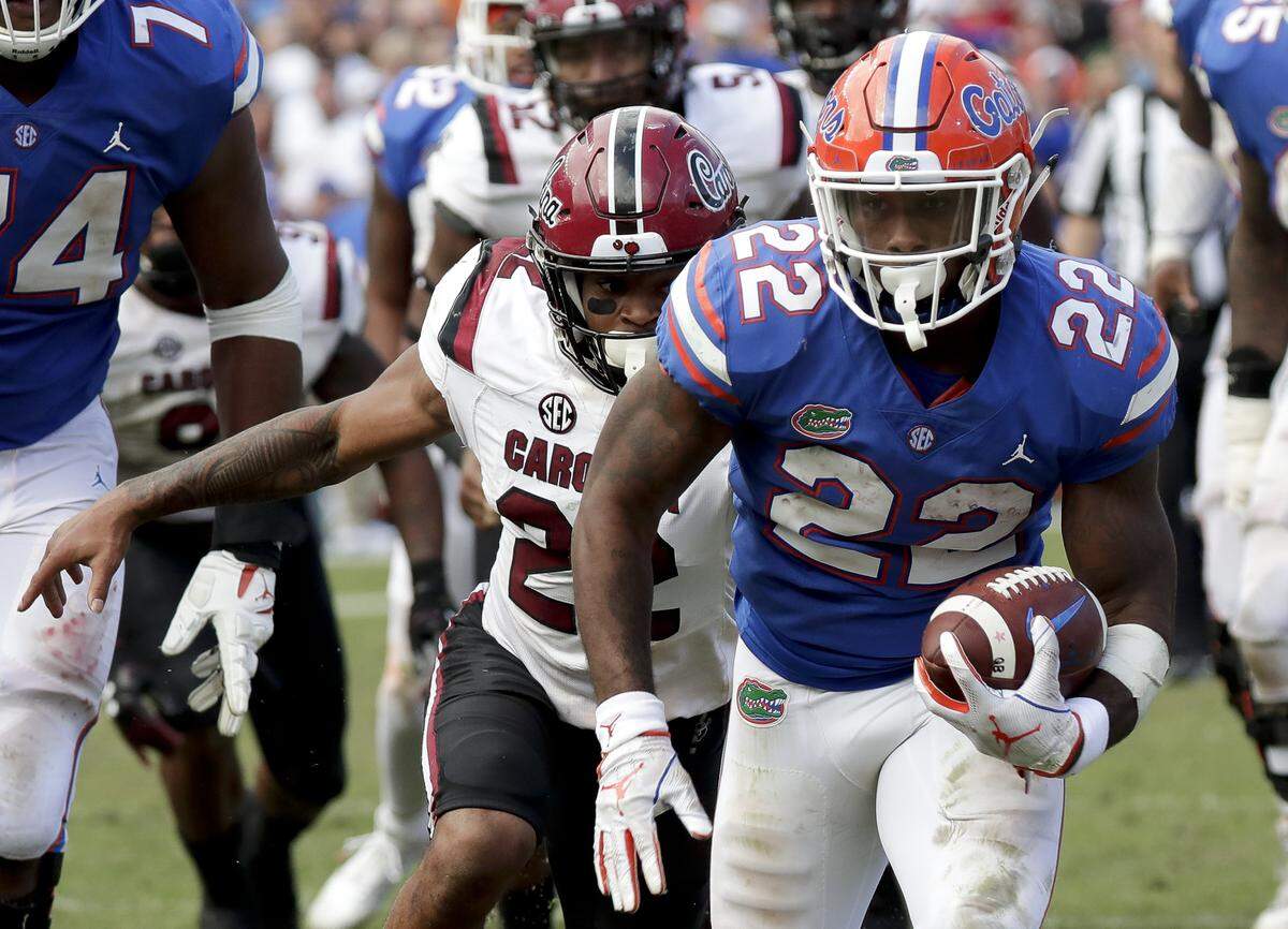 Florida running back Lamical Perine, front right, breaks away from South Carolina defensive back Steven Montac, left, for a 23-yard touchdown run during the second half of an NCAA college football game, Saturday, Nov. 10, 2018, in Gainesville, Fla.
