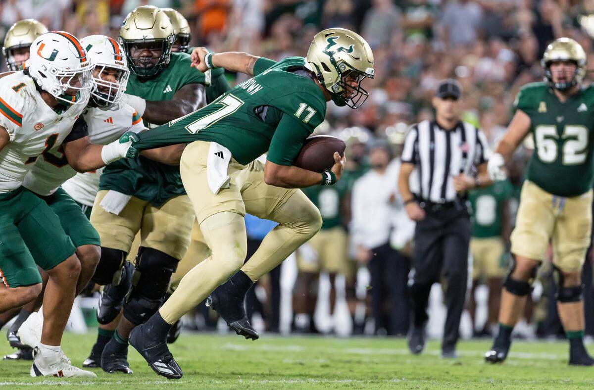 Miami Hurricanes linebacker Francisco Mauigoa (1) and defensive lineman Akheem Mesidor (3) try to stop South Florida Bulls quarterback Byrum Brown (17) from running with the ball in the first half of their NCAA college football game at the Raymond James Stadium on Saturday, Sept. 21, 2024, in Tampa, Fla.