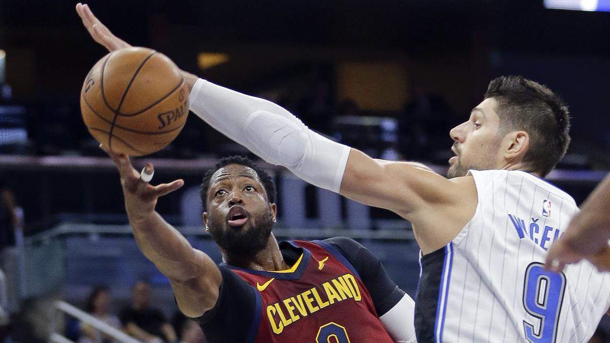 Cleveland Cavaliers' Dwyane Wade, let, makes a basket as he gets past Orlando Magic center Nikola Vucevic during the first half of an NBA preseason basketball game on Oct. 13, 2017, in Orlando.