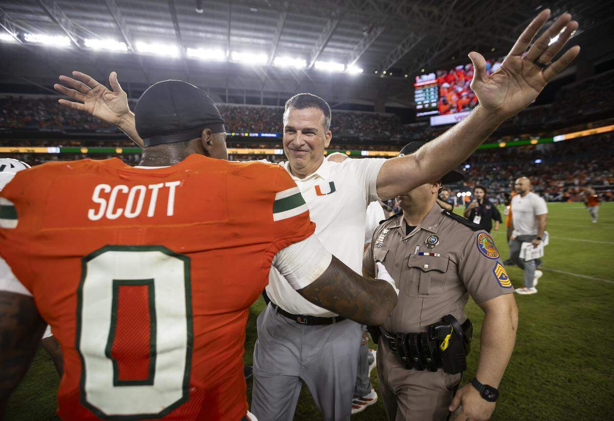 Miami Hurricanes head coach Mario Cristobal hugs defensive back Keionte Scott (0) after they defeated the Notre Dame Fighting Irish in their NCAA football game at Hard Rock Stadium on Sunday, Aug. 31, 2025, in Miami Gardens, Fla.