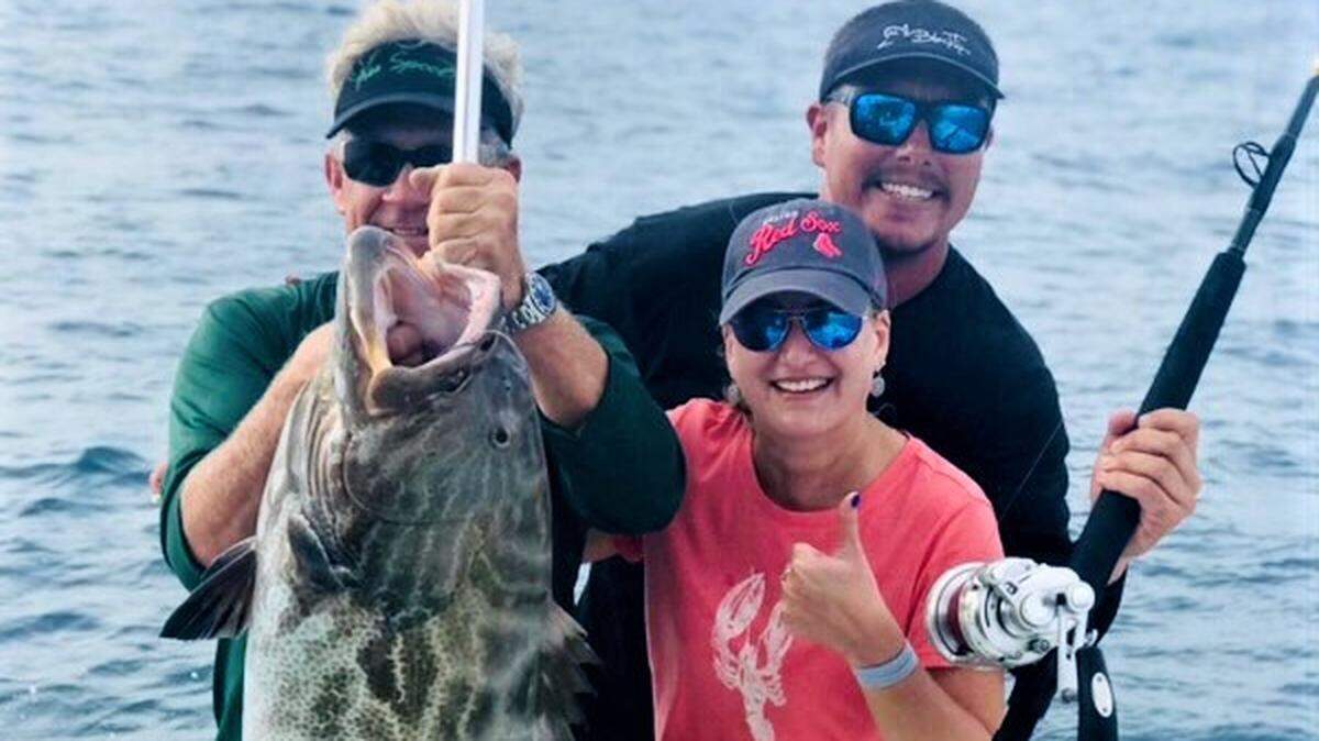 Capt. Dennis Forgione, left, holds a 48-pound black grouper caught by his female angler on his charter boat Free Spool.