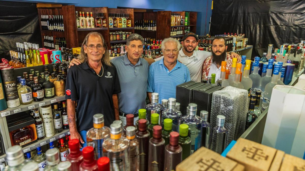Los antiguos propietarios de Sunset Corners, los primos Larry Solomon (extremo izquierdo) y Michael Bittel (tercero por la derecha) posan con los nuevos dueños Eduardo Cruz y su hijo Kevin Cruz, propietarios de la cadena de licores Jensen's, junto al gerente de la tienda Bruno Barbato (extremo derecho), en el emblemático negocio familiar Sunset Corners en 8701 Sunset Dr, en Miami, el 1 de junio de 2024.
