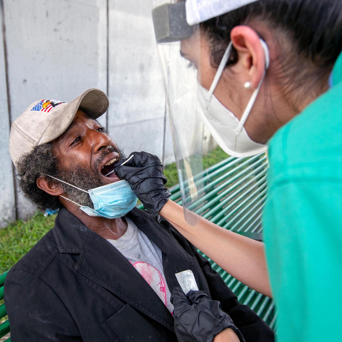 Shelby Ewing has his mouth swabbed to test for the novel coronavirus by a volunteer medical practitioner near St. John Institutional Missionary Baptist Church in Overtown, Florida on Friday, April 24, 2020. Dr. Armen Henderson, Dream Defenders and coalition of community organizations and medical providers launched expanded services for the homeless in Overtown, including coronavirus testing for those without homes or regular access to health care.