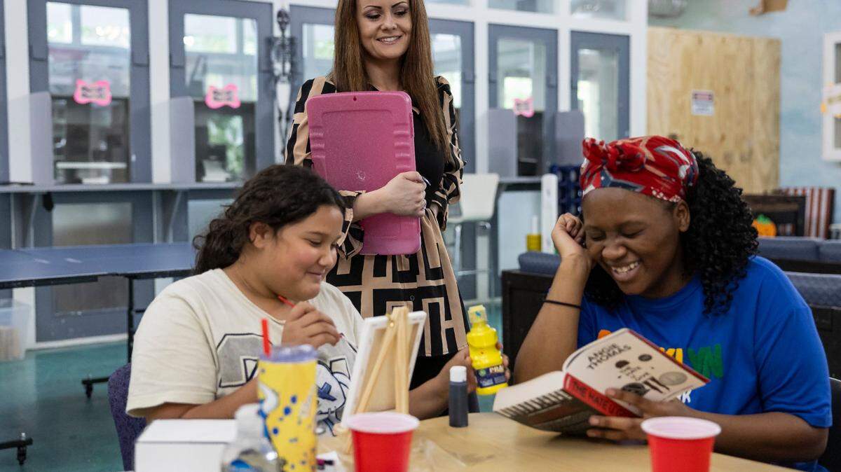 Samantha Roberts, center, the Miami shelter manager, talks with Bianca, left, and Jada, right, who are staying at Miami Bridge Youth and Family Services, participate in various activities on Friday, Oct. 18, 2024, in Miami, Fla. Miami Bridge is a nonprofit organization in Miami-Dade County that provides emergency shelter, food and counseling for troubled youth and their families.