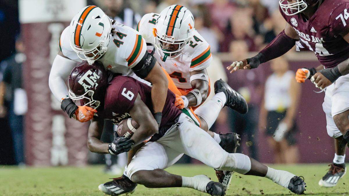 Miami Hurricanes defensive lineman Antonio Moultrie (44) and safety Kamren Kinchens (24) take down Texas A&M Aggies running back Devon Achane (6) in the second half at Kyle Field, Bryan College Station, Texas on Saturday, September 17, 2022.