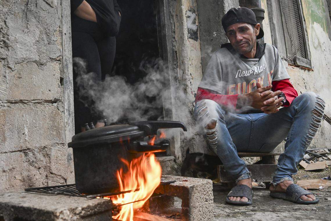 A man cooks food on a pot on a wood fire during a blackout in the Poey neighborhood of Havana on January 28, 2026. 