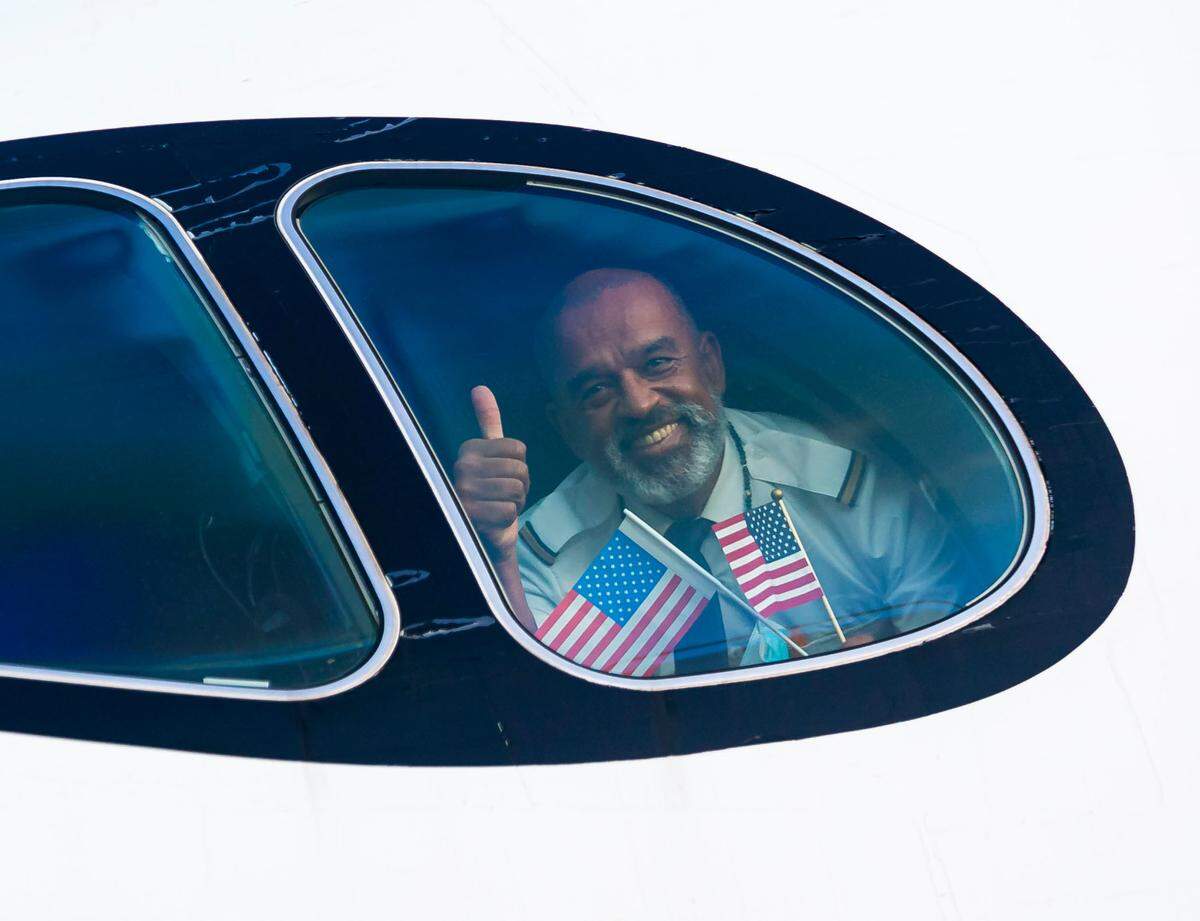 Lufthansa crew member Dominique Buhe holds two American flags after arriving at the Miami International Airport from Munich, Germany, on Nov. 8, 2021, the day travel restrictions for many foreigners had been lifted in the United States as long as they show proof of vaccination.