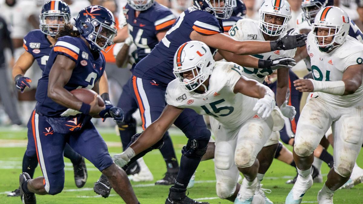 Miami Hurricanes defensive lineman Gregory Rousseau (15) dives to tackle Cavaliers quarterback Bryce Perkins (3) in the third quarter of a football game versus Virginia at Hard Rock Stadium in Miami Gardens on Friday, October 11, 2019.