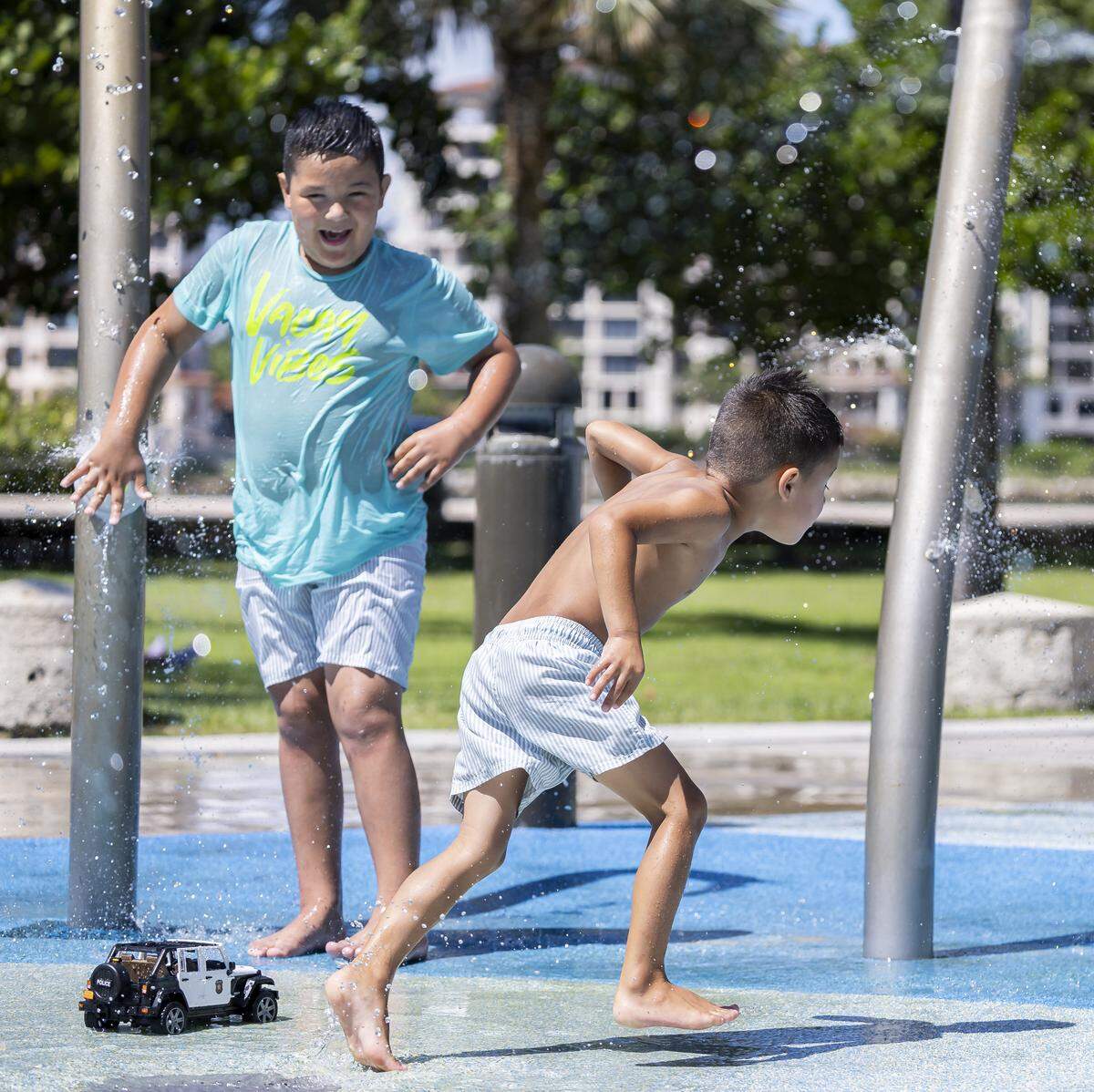 Mateo Tuesta, 7, activates a splash pad as his brother, Tiago Tuesta, 4, runs to avoid the water at South Pointe Park as hot weather moves through the area on Friday, Aug. 15, 2025, in Miami Beach, Fla. Forecasters have issued heat advisories throughout the summer in South Florida, with temperatures at times feeling as hot as 109 degrees.