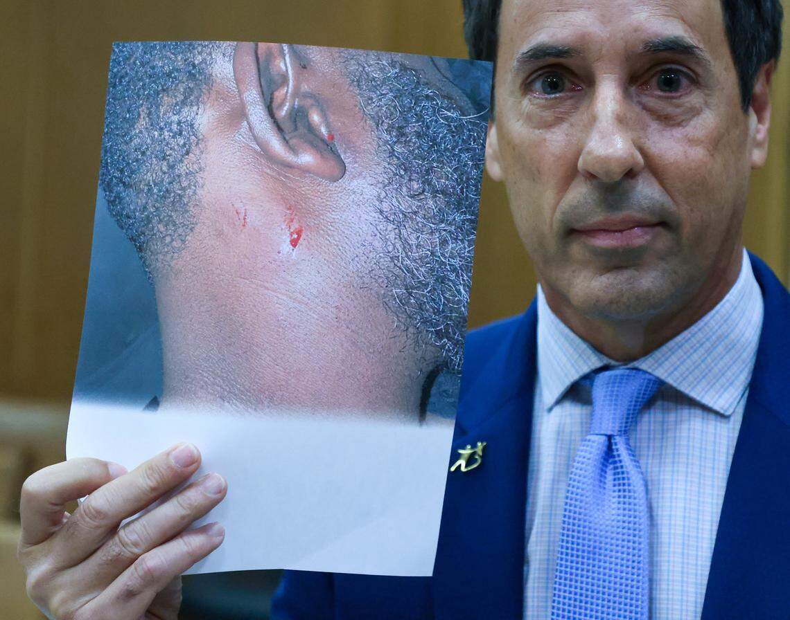 Mark Eiglarsh, right, Antonio Brown's attorney, holds a photo of Zul-Qarnain Kwame Nantambu 's neck as he challenges the account of the shooting after he filed a written plea of “not guilty” to the attempted murder charge in Bond Court (Courtroom 1-5) with Judge Mindy S. Glazer, center, presiding at the Richard E. Gerstein Justice Building on Wednesday, November 12, 2025, in Miami, Florida.