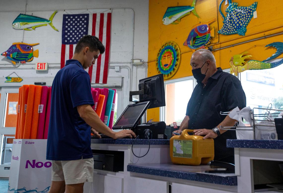 Pinch A Penny employee Julio Villamar, 19, checks out customer Alex Sanchez at the franchised retail pool supply and service company, 11035 Bird Road in Miami, on Saturday, Nov. 13, 2021.
