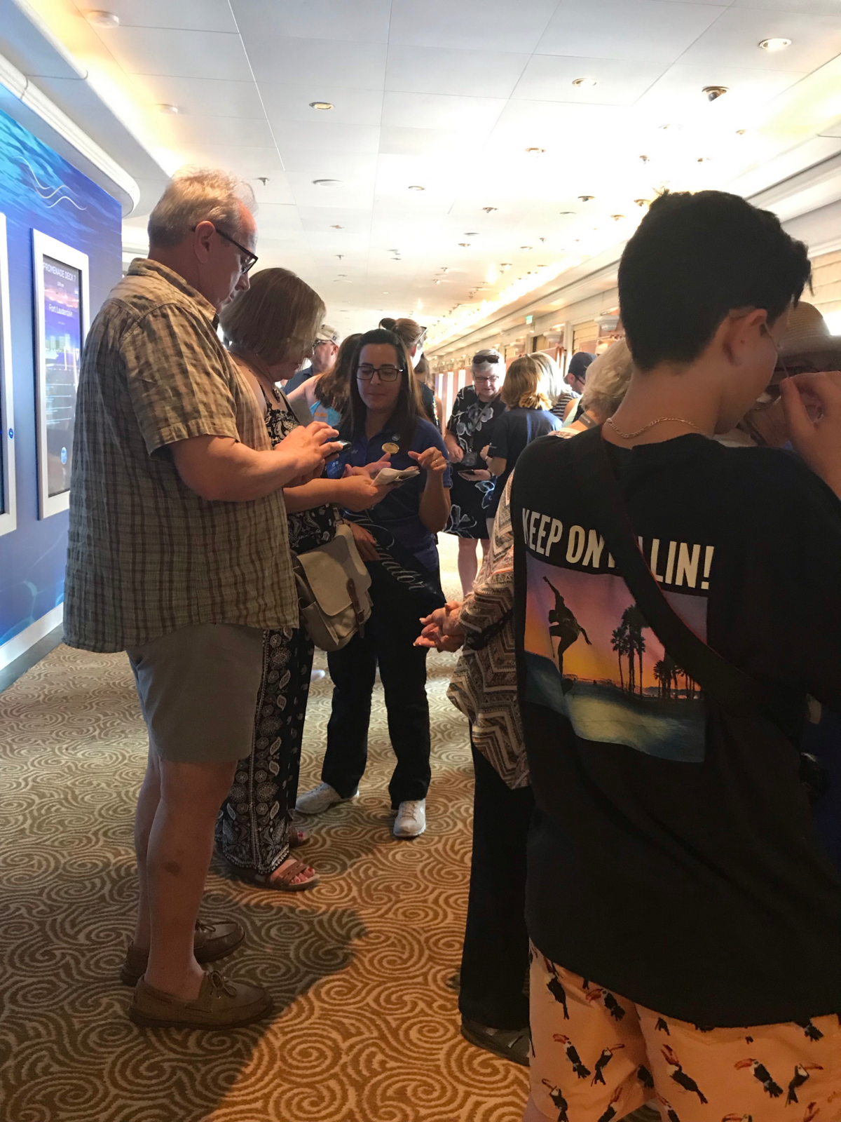 Passengers aboard the Caribbean Princess gather around the Ocean Medallion tech help desk to learn about the new service from Carnival Corporation on Feb. 25, 2019.
