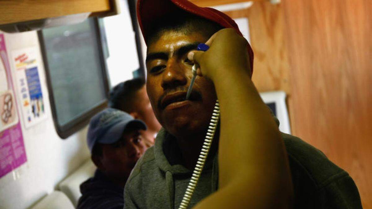 Outreach worker Jessica Maciel takes a migrant farm worker’s temperature  during a check-up in a mobile clinic on a spinach farm near Wellington, Colorado.