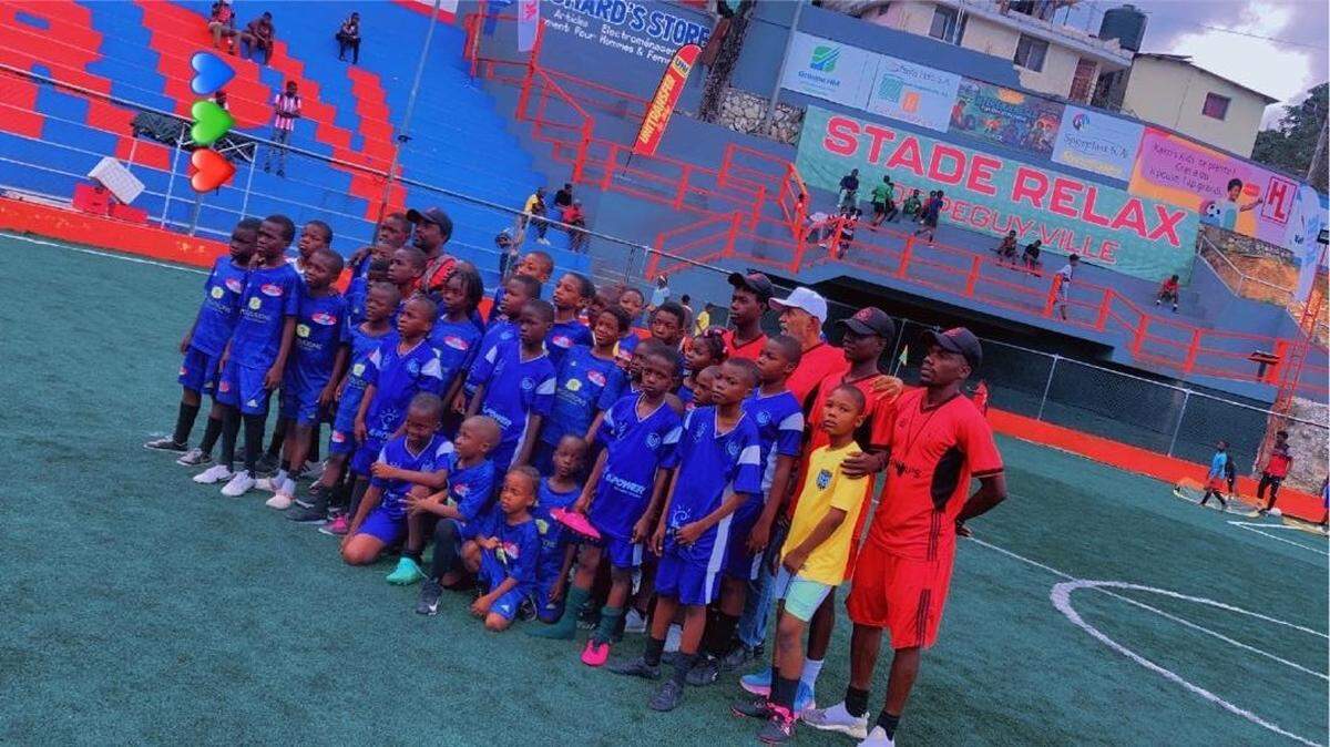 Patrice Millet, third from the right in back row, stands with some of the players in his Olympique École de Football in Port-au-Prince. He is standing in front of Josué St. Vilus, an 11-year-old goalkeeper who was killed on Saturday, May 16, 2026, during a surge in gang violence.