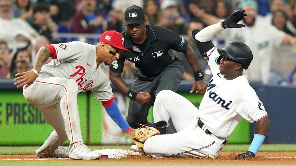Miami Marlins’ Jesus Sanchez, right, beats the throw to Philadelphia Phillies first baseman Johan Camargo, left, for a triple during the fifth inning of a baseball game, Friday, April 15, 2022, in Miami. (AP Photo/Lynne Sladky)