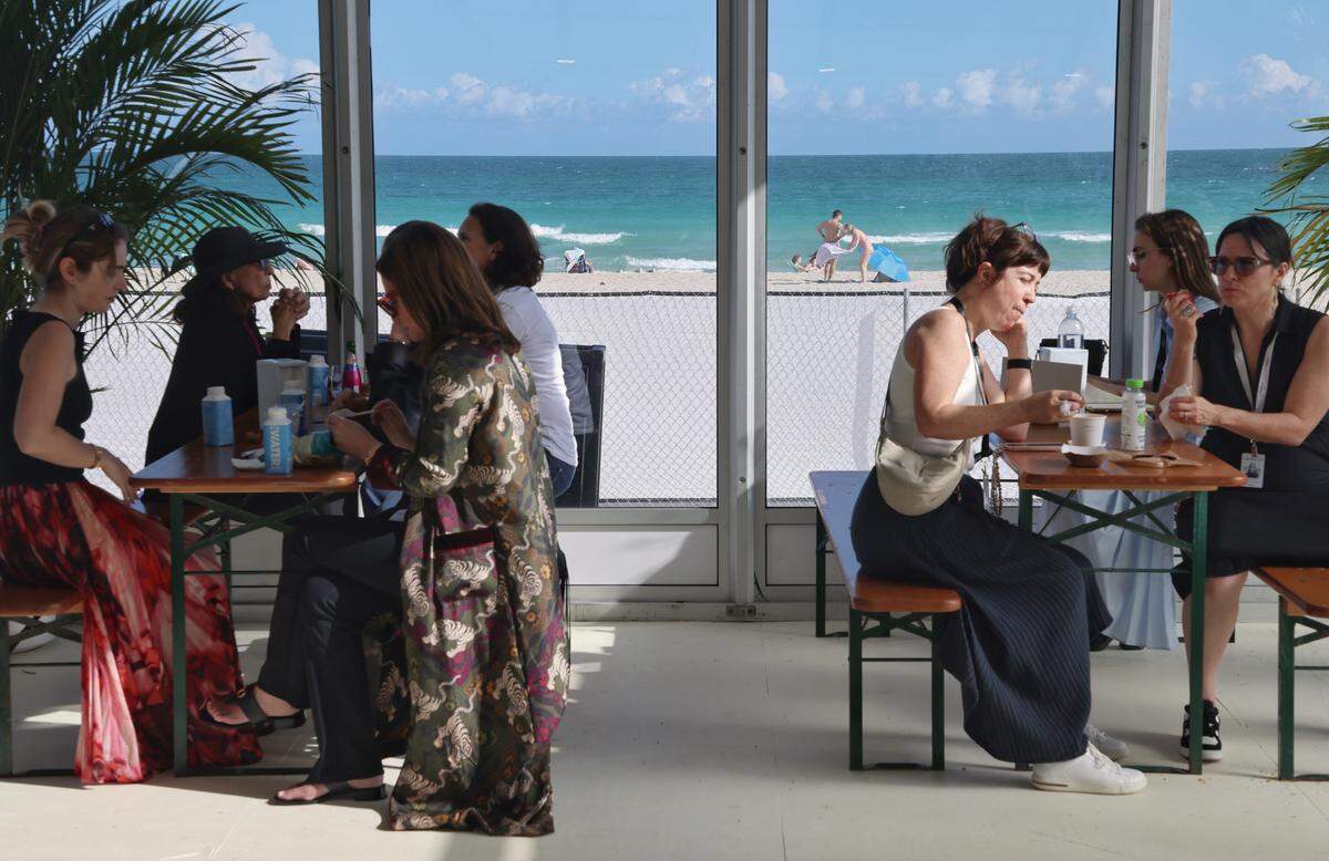 Miami Beach, FL, December 2, 2025 -Untitled Art attendees enjoy a quick snack as beachgoers enjoy blue sunny skies of South Florida.