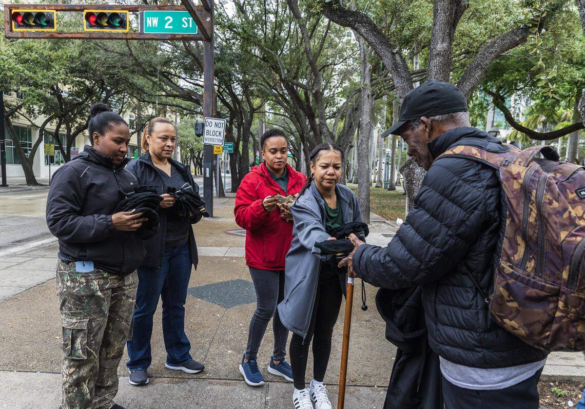 From left, Shaunie Chambers, Katherine Martinez, Nely Cabral and Magalis Rivaflecha, with the City of Miami, give cold-weather items to a homeless man on Saturday, Jan. 31, 2026, near the Stephen P. Clark Center. 