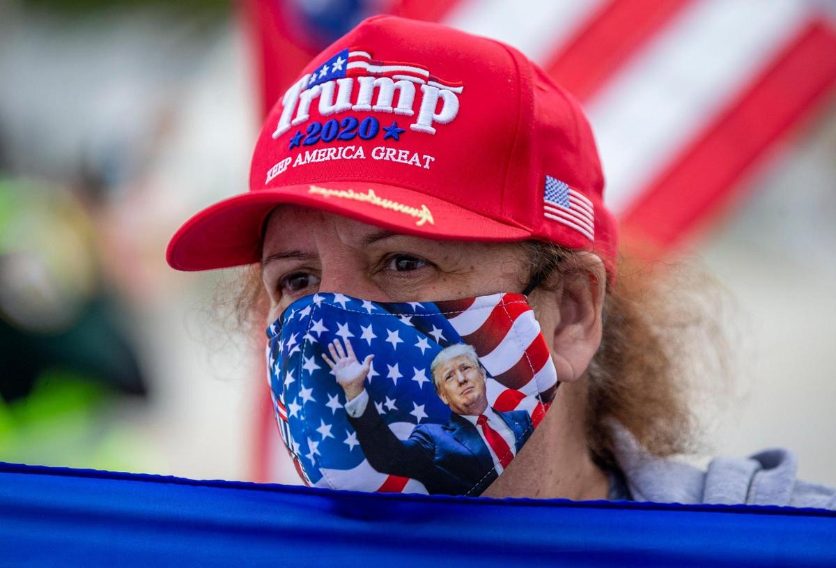 Maritza Betancourt awaits the arrival of U.S. President Donald Trump and his motorcade along Southern Boulevard on his way to Mar-a Lago in Palm Beach on Wednesday, Jan. 20, 2021.