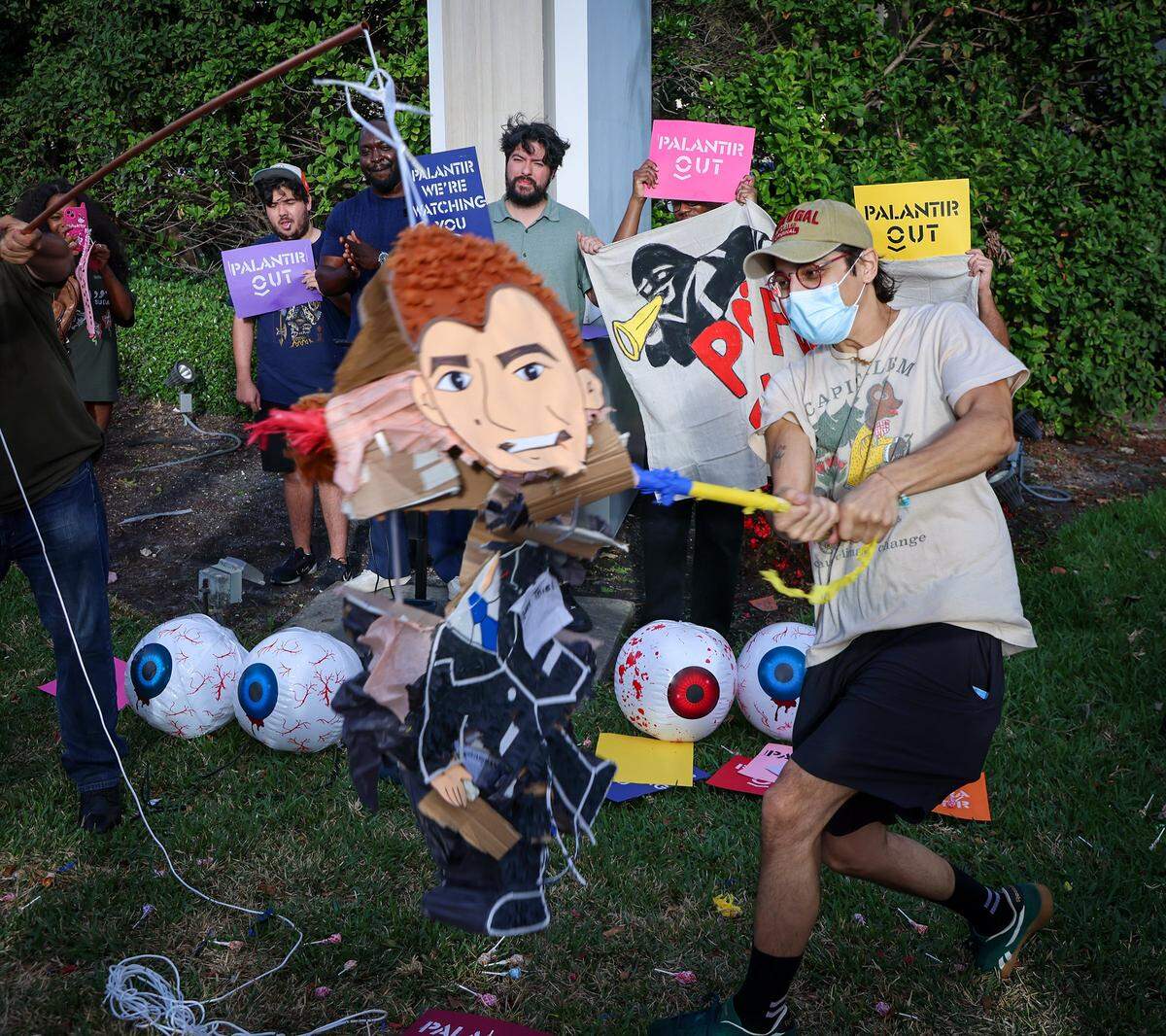 A protestor swings a stick a piñata of Peter Thiel as a small group gathered around the mall entrance, wielding bright signs that conveyed messages calling for increased accountability and transparency from the tech giant on Tuesday, March 3, 2026 at the entrance of Aventura Mall in Aventura, Florida.