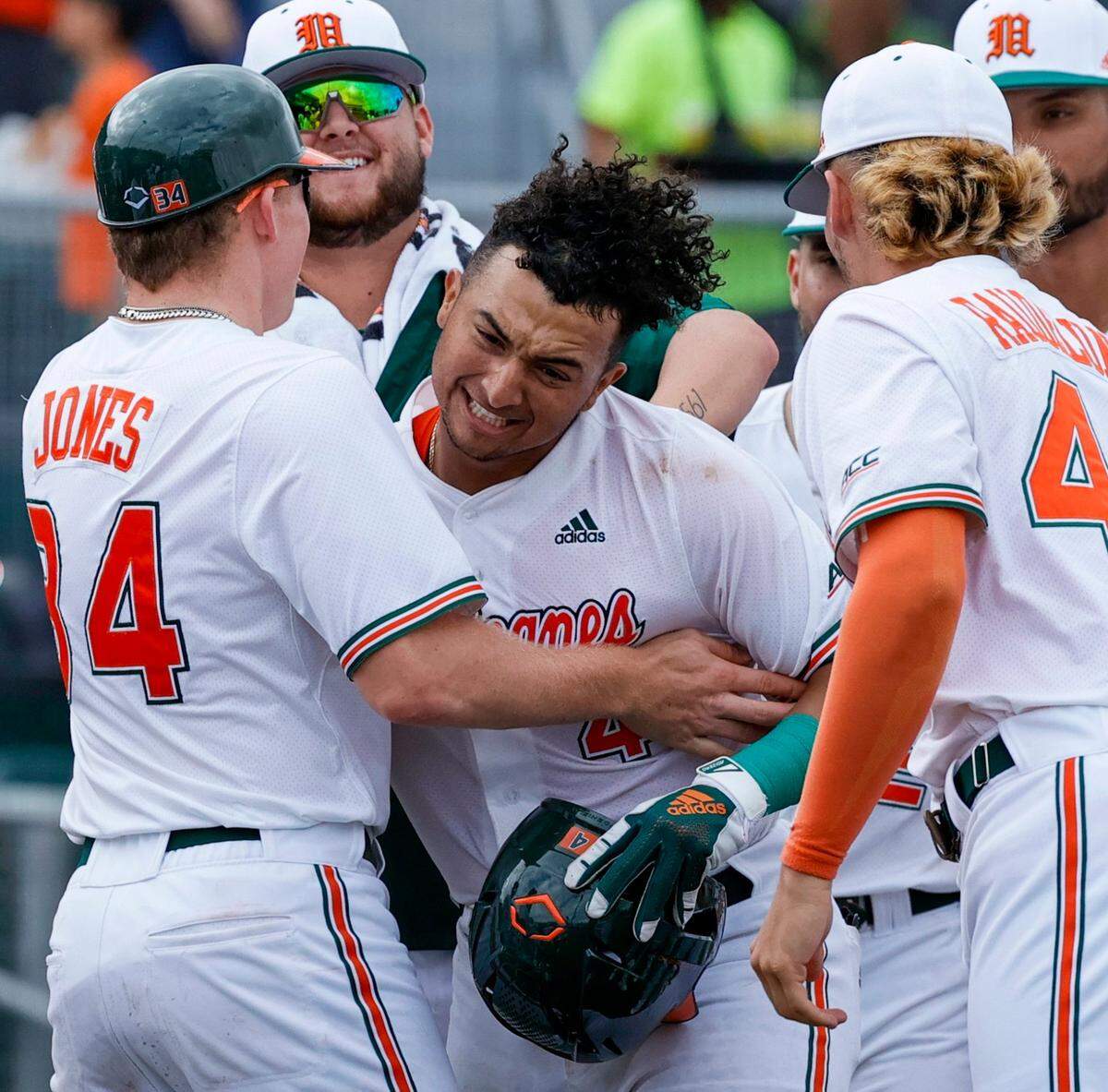 Miami Hurricanes catcher Maxwell Romero Jr. (4) is congratulated by teammates after hitting a three run home run during the third inning of an NCAA baseball game against the Towson Tigers in Alex Rodriguez Park at Mark Light Field on Sunday, February 20, 2022 in Coral Gables.
