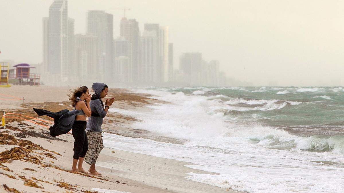 With high-rise condos in the background, a couple walk on the beach by the 71st Street area in Miami Beach as Hurricane Isaias loomed on Aug. 1, 2020.