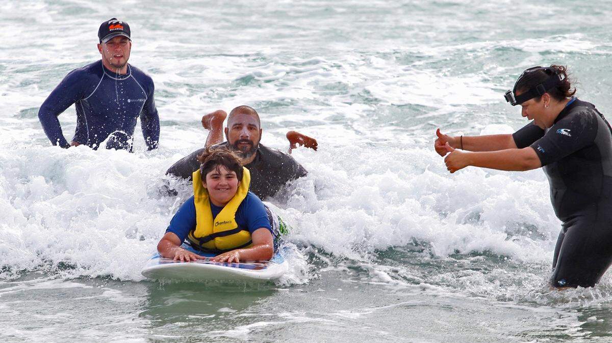 Brandon Rozencwaig 12, learns to surf from Miami Beach lifeguard Rafael Ruiz as lifeguard Julio Espinosa, left, and Miami Beach Parks and Recreation supervisor Edith Guerra look on at the Ninth Annual Surf Camp at South Pointe Park on Miami Beach. The annual camp includes a week of surfing, swimming skills and basic oceanography for kids with autism spectrum disorders. The camp is put on by the UM-NSU Center for Autism and Related Disabilities (CARD) and the City of Miami Beach.