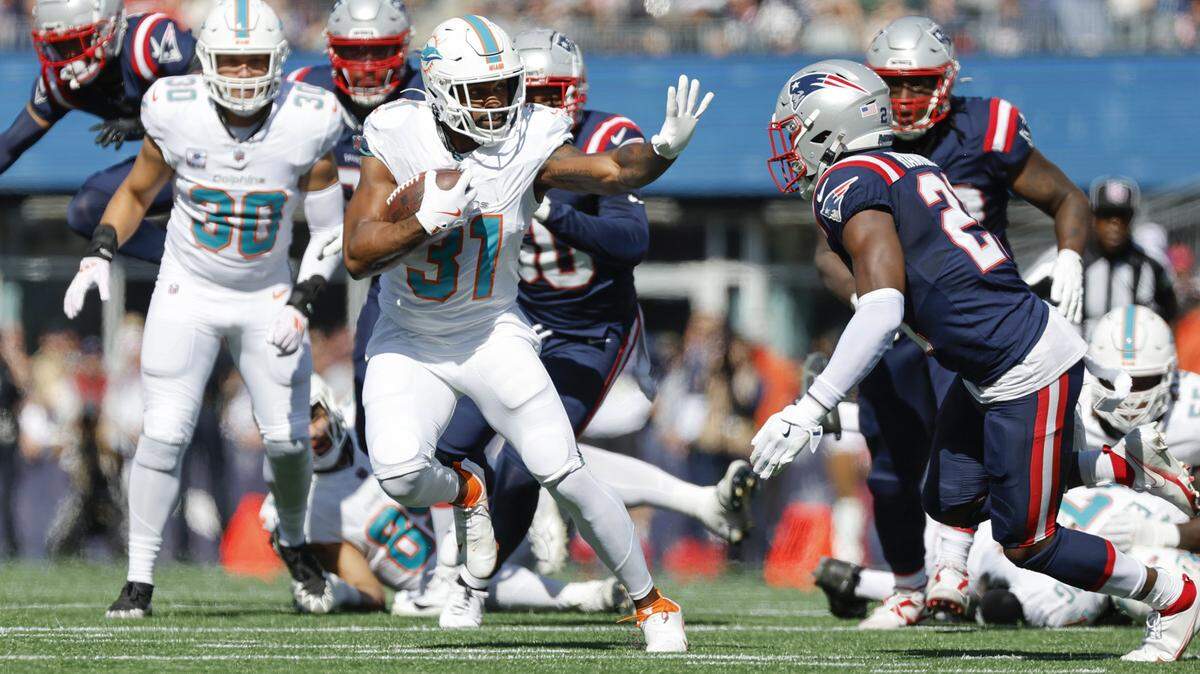 Miami Dolphins running back Raheem Mostert (31) rushes as New England Patriots safety Jaylinn Hawkins (21) defends in the first half of their NFL football game at Gillette Stadium in Foxborough, Massachusetts on Sunday, October 6, 2024.