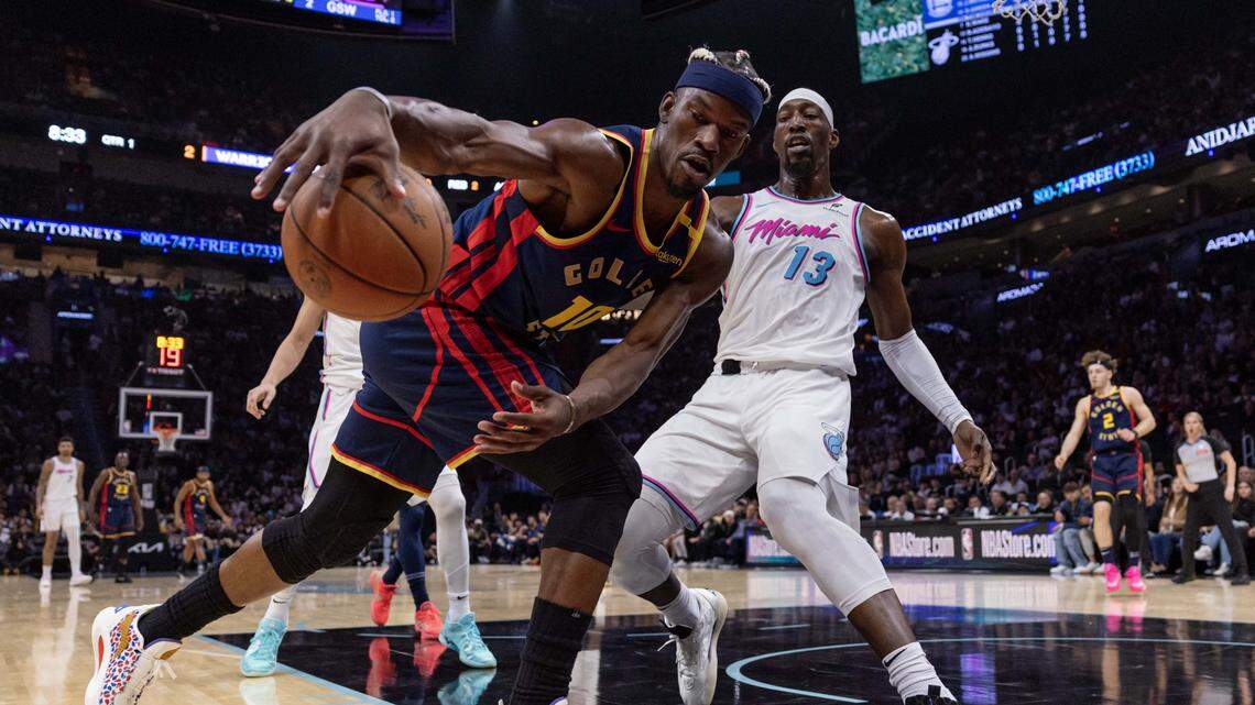 Golden State Warriors forward Jimmy Butler III (10) grabs the loose ball while defended by Miami Heat center Bam Adebayo (13) during the first half of an NBA game at Kaseya Center on March 25, 2025, in Miami.