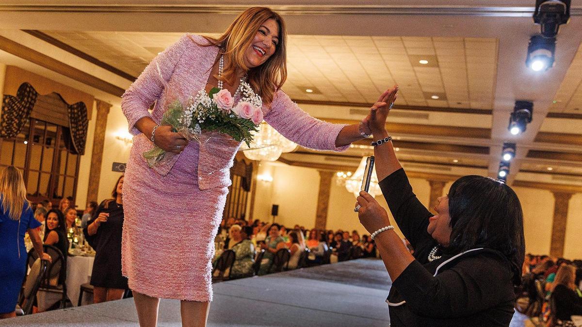 Madeline Pumariega, president of Miami Dade College, shares a high five after receiving the Latina Pioneer of the Year Award at the 22nd Hispanic Women of Distinction luncheon Friday, Aug. 25, 2023 at Signature Grand event venue in Davie.