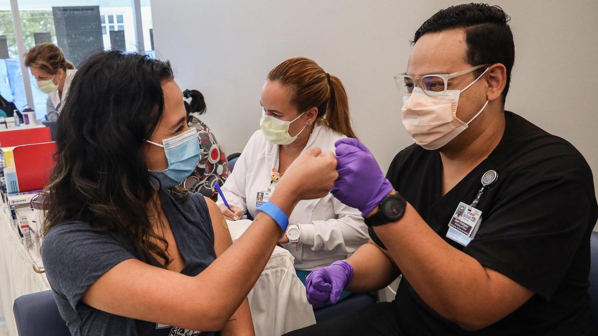 Camila Guti’errez (izq), de 21 años y estudiante de FIU, saluda al estudiante de Farmacia Jason Rodr’iguez (der) después de vacunarse en Miami, Florida, el 15 de abril de 2021.