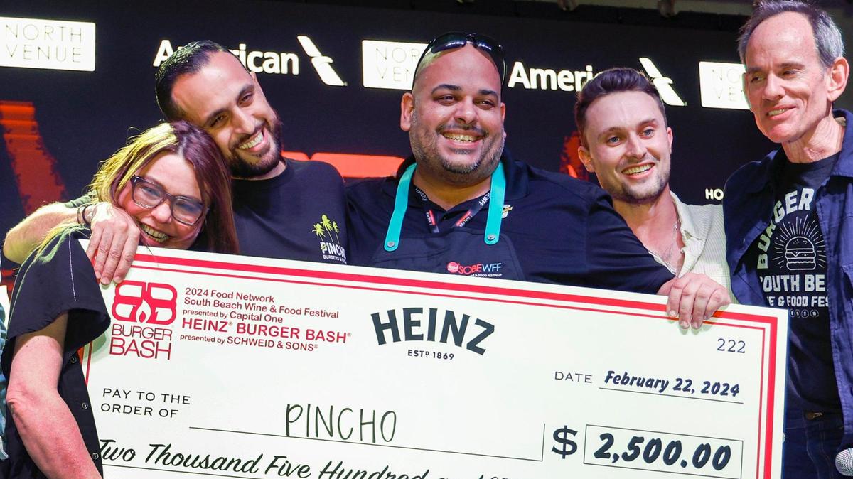 Rachel Ray gets a hug from Pincho Factory founder Otto Othman, who’s next to chef Adrian Sanchez as Pincho is awarded the People’s Choice Award during Burger Bash at the South Beach Wine & Food Festival on Miami Beach.