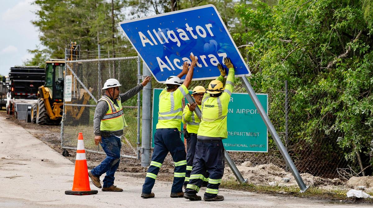 Workers install a permanent Alligator Alcatraz sign at the new state immigration detention facilty in the Everglades.